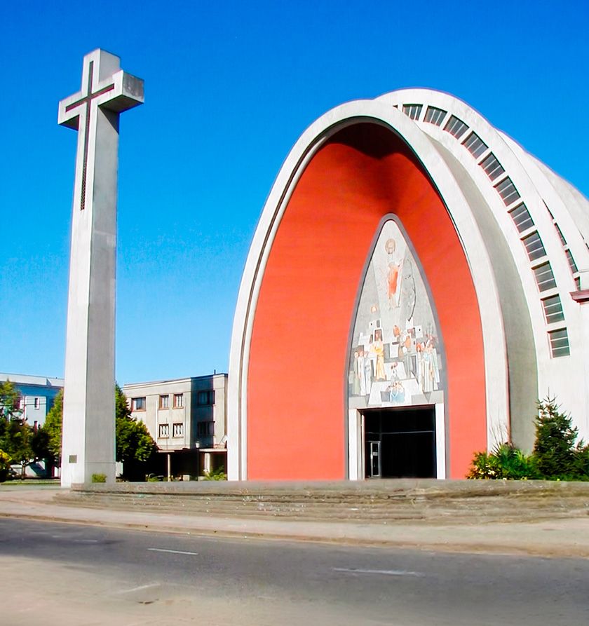 Catedral de Chillán con su característica estructura de arcos parabólicos rojos y la Cruz Monumental en primer plano.