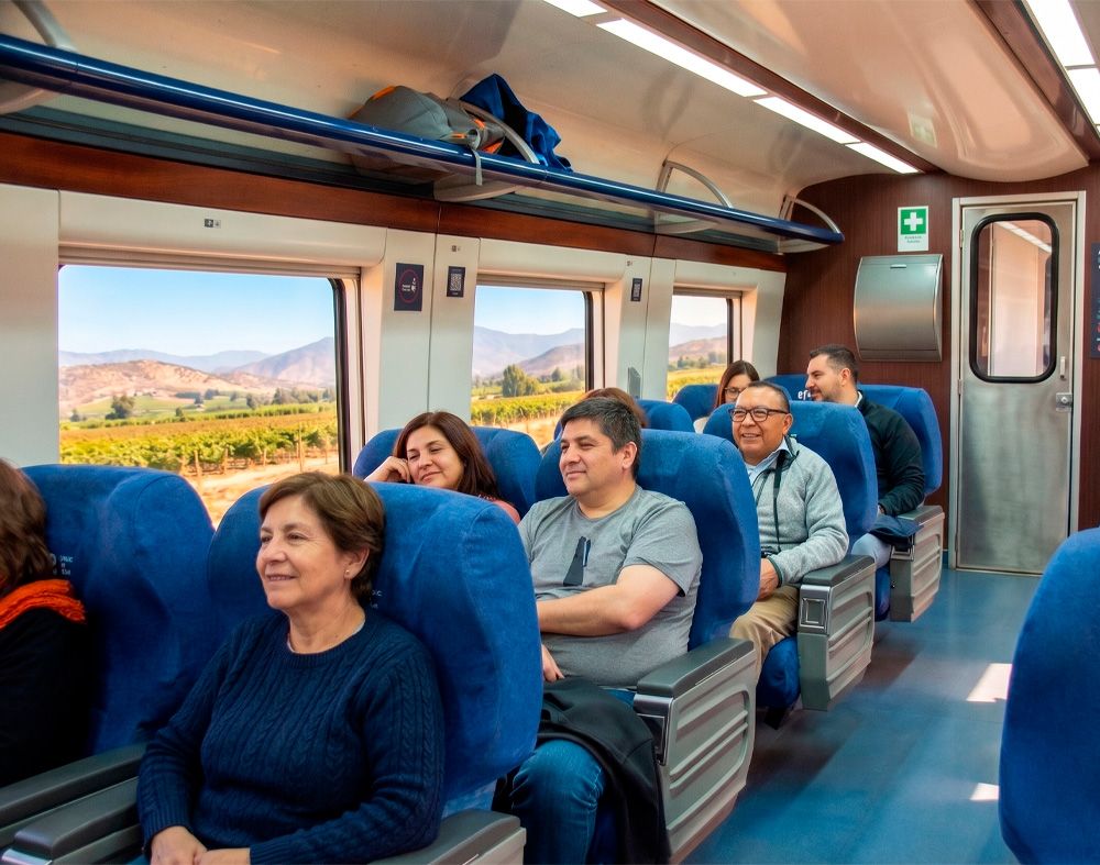 Interior de un moderno tren de EFE Trenes de Chile, mostrando pantallas de información digital, mesas integradas y pasamanos azules de accesibilidad universal, destacando la innovación de la flota.
